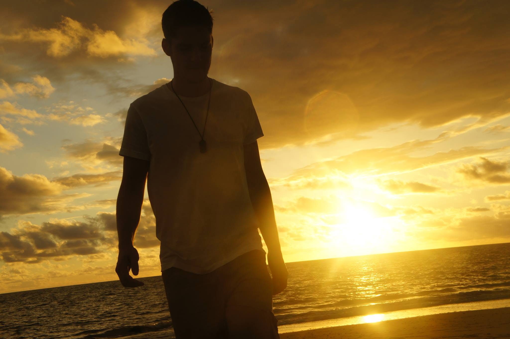 Jonathan silhouetted against a golden ocean sunset